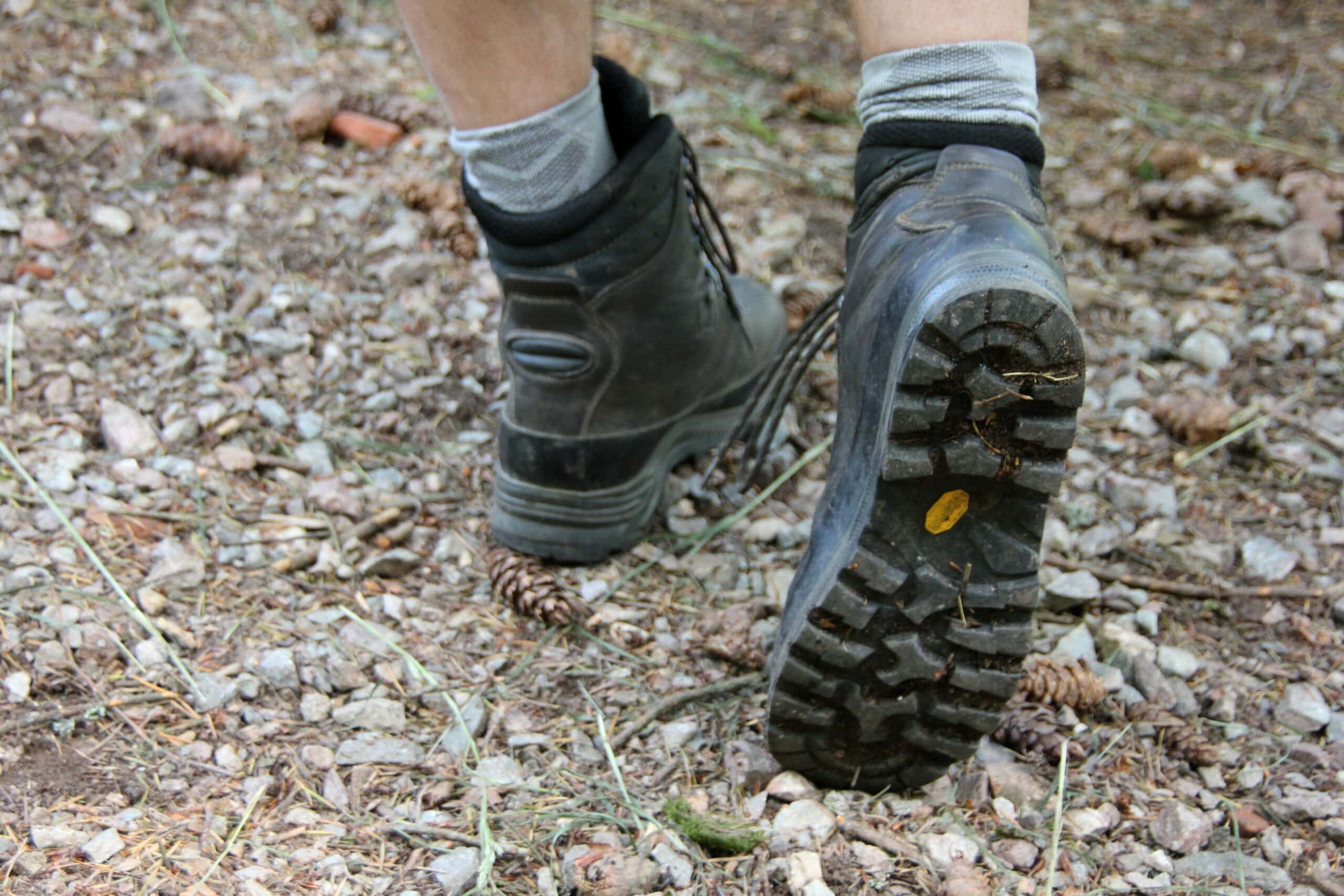 Wanderstiefel mit Profilsohle auf moosigem Waldboden mit Laub und kleinen Steinen, typisch für Waldwege im Naturpark.