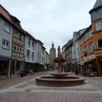 Historischer Marktplatz im Odenwald mit Brunnen und Statue, umgeben von Fachwerk- und Sandsteinbauten, typisch für ländliche Regionen des Neckartal-Odenwalds.