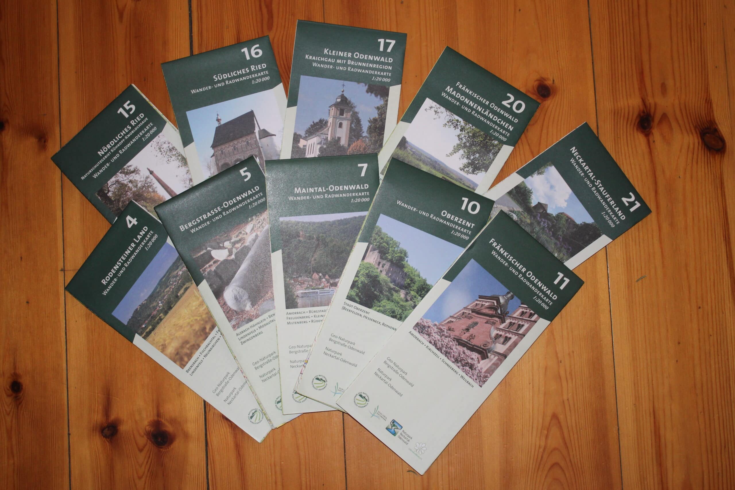 Sammlung von Wander- und Radwanderkarten des Naturparks Neckartal-Odenwald und Geo-Naturparks Bergstraße-Odenwald im Maßstab 1:20.000, nummeriert und mit Landschaftsmotiven.